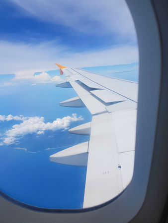 The wings of the plane on a cloud background and the bright sky. To shoot through a plane windowの写真素材