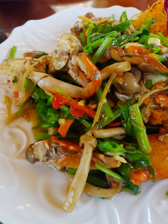 Crab fried with curry powder in a white dish placed on a brown wood tableの写真素材