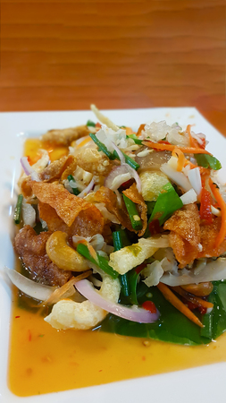 Thai Crisp Salad in a white dish that is placed on a wooden tableの写真素材