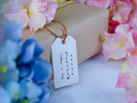Brown gift box with greeting cards on Mother's Day  and placed in the midst of blue and pink flowersの写真素材