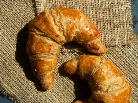 Fresh butter croissants on a mat that is placed on a dark gray wood tableの写真素材