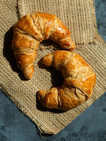 Fresh butter croissants on a mat that is placed on a dark gray wood tableの写真素材