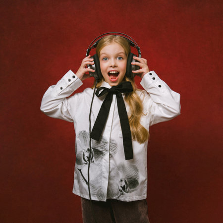 Portrait of a girl with headphones listening to music on a red backgroundの写真素材