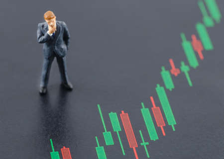 miniature business man standing on the candlestick stock chartの写真素材