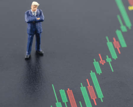 miniature business man standing on the candlestick stock chartの写真素材