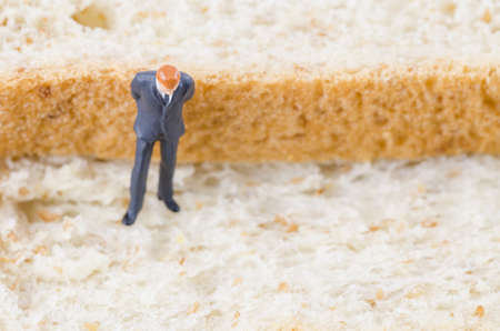 miniature businessman standing on the whole wheat bread