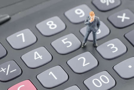miniature businessman standing on the calculatorの写真素材