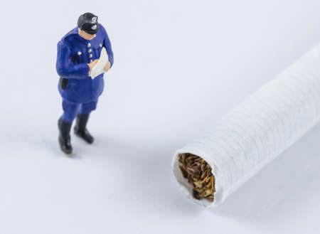 miniature policeman standing beside cigaretteの写真素材