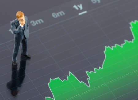 miniature businessman standing on the stock graph in tabletの写真素材
