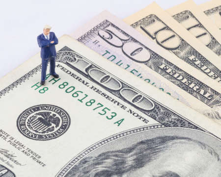 miniature businessman standing on the US dollar banknoteの写真素材