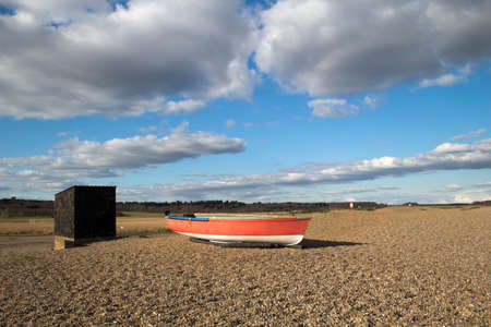 Red fishing boat and shed on Dunwich Beach in Suffolk, Englandの写真素材