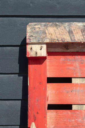 Orange pallett leaning against a black wooden shedの写真素材
