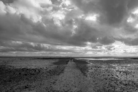 Black and white image of a pathway going out into the sea at Westcliff, Essex, Englandの写真素材