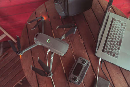 Drone quadcopter with a flight controller and notebook on the old wooden background.