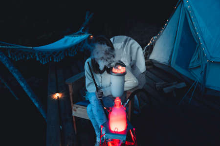 Girl smokes a hookah on the nature near the tent. Camping outdoor recreation.のeditorial素材