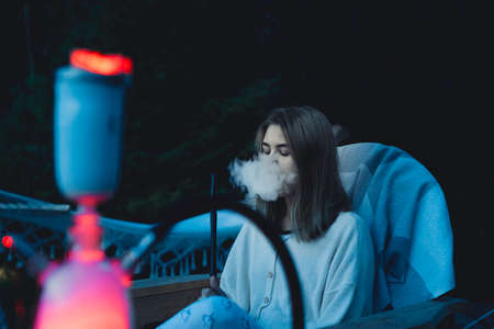 Girl smokes a hookah on the nature near the tent. Camping outdoor recreation.のeditorial素材