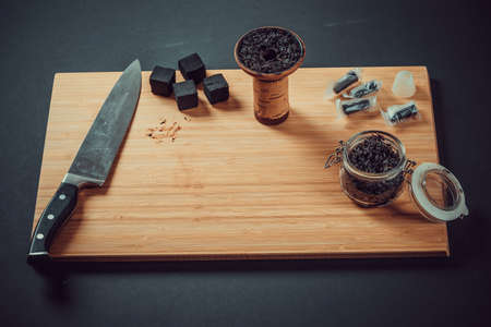 Hookah making on a wooden board and accessories. Hookah bowl, with tobacco stuffed into it.の写真素材