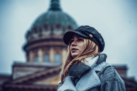 Traveler girl in warm clothes and a scarf turned to the camera on the background of Kazan Cathedral. Russia. Saint Petersburg.のeditorial素材