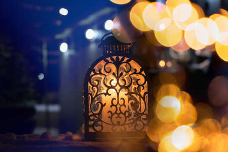 A Christmas winter woodland snowing scene with a warm glowing lamp on a wooden table at night....