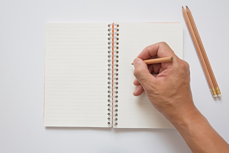 open note book lay on white background and  hand hold pencilの写真素材