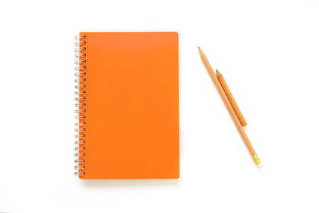 orange covered note book lay on white background with brown pencilの写真素材