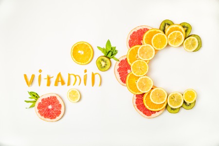 Vitamin C letters made of citrus fruits - lemon, grapefruit, kiwi and orange slices on white backgroundの写真素材
