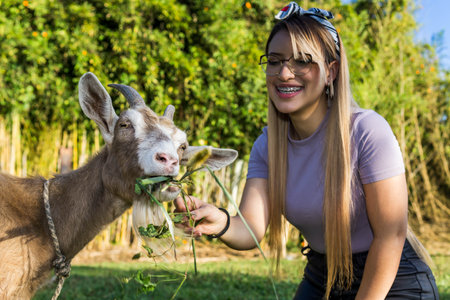 Women Day, March 8, empowered and self-confident woman. Woman expressing comfort and freshness. Happy woman in nature. Girl with glasses. Woman petting a goat.の写真素材