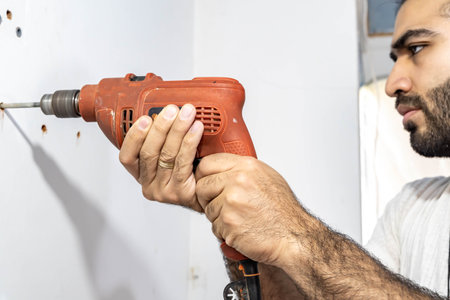 Man drilling in the wall of his house