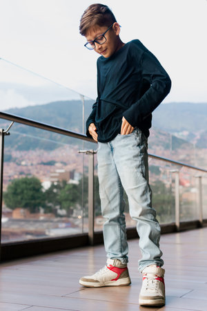 Latino boy in black shirt running down the hallway of a tall building, games and fun. Vacations, children's day, family day.の写真素材