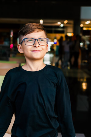 Latino boy in black shirt running down the hallway of a tall building, games and fun. Vacations,...