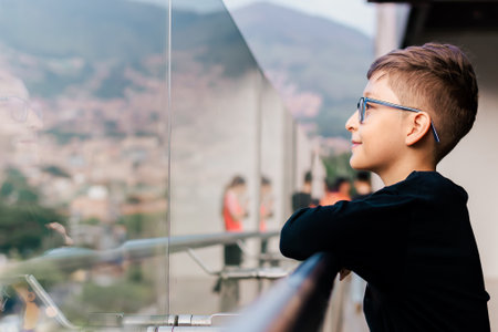 Portrait of a boy in glasses looking out the window of a building