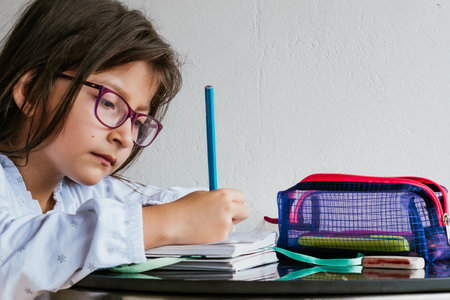 Latina girl in glasses doing chores at home. Coloring a notebook. Back to school. Childhood and...