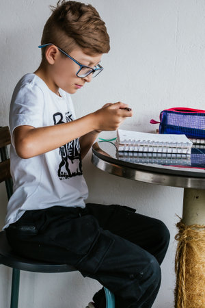 Latin boy with glasses drawing a picture in his notebook. Back to school, childhood. Homework and classes.の写真素材