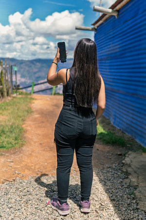 Young Colombian woman using smartphone at scenic overlook in Medellinの写真素材