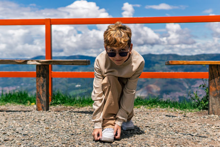 boy tying his shoelaces outdoors on a sunny day, childhood moment of independence and focusの写真素材