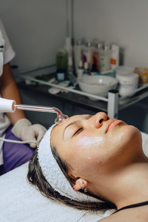Photo of a young Colombian mestiza woman in a beauty spa where she has a facial cleansing and goes...