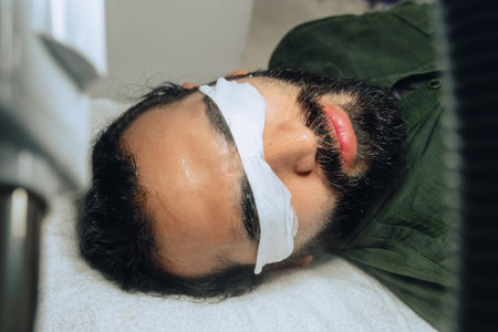 Professional exfoliation, moisturizing and facial cleansing treatment photo for a bearded Colombian...