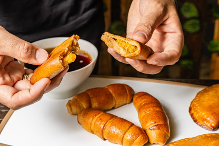 close-up horizontal photo of adult male hands opening whole wheat empanada with pineapple inside,...