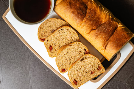 Horizontal top view photo of traditional artisan whole wheat bread with guava jam next to a cup of...
