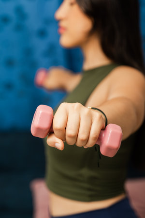 Close-up of woman's hand lifting pink dumbbell during indoor workout with copy space.の写真素材