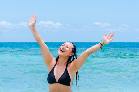 Colombian woman with braids raising arms joyfully in turquoise sea with copy space on Mucura Island, Colombian Caribbean.の写真素材