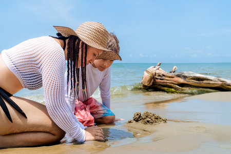 Colombian aunt and nephew playing with sand at Caribbean beach. Family moment in CoveÃ±as.の写真素材