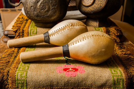 Traditional maracas on floral woven textile with engraved metal vessels in Colombian interior.