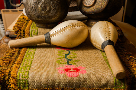 Maracas on floral woven textile with engraved metal vessels in interior.の写真素材