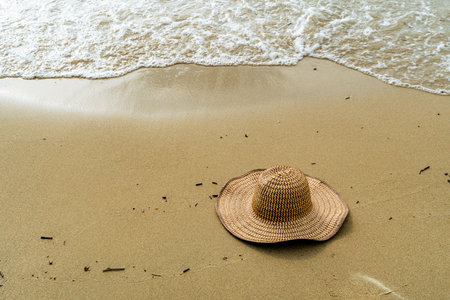 Straw hat rests on the sand in Covenhas near the shoreline, evoking quiet presence and tropical...