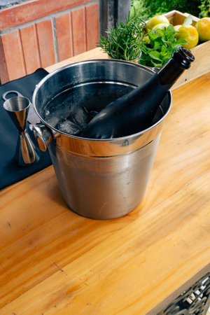 Metal ice bucket with wine bottle, citrus, and herbs in drink preparation areaの写真素材