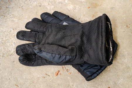 Black winter gloves with grip texture placed on concrete surface