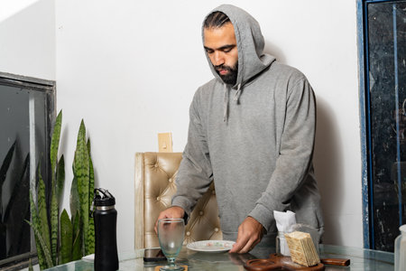 Person clearing plate and glass after eating Colombian arepa at breakfast table.の写真素材