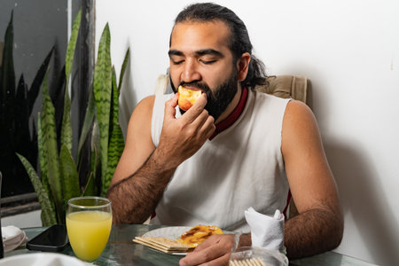 Person eating peach with Colombian arepa and crackers at breakfast table.の写真素材