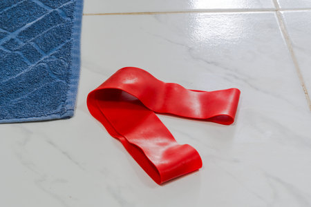 Red resistance band on tiled floor with blue towel.